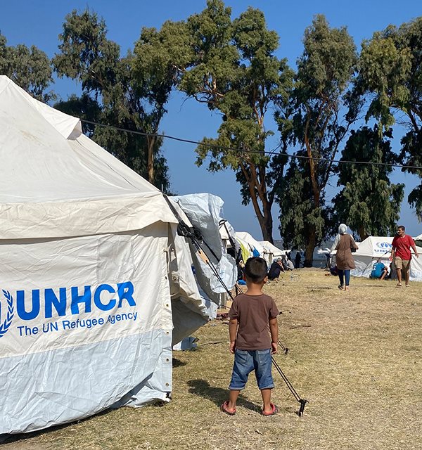 Liten gutt foran teltet i ny flyktningleir