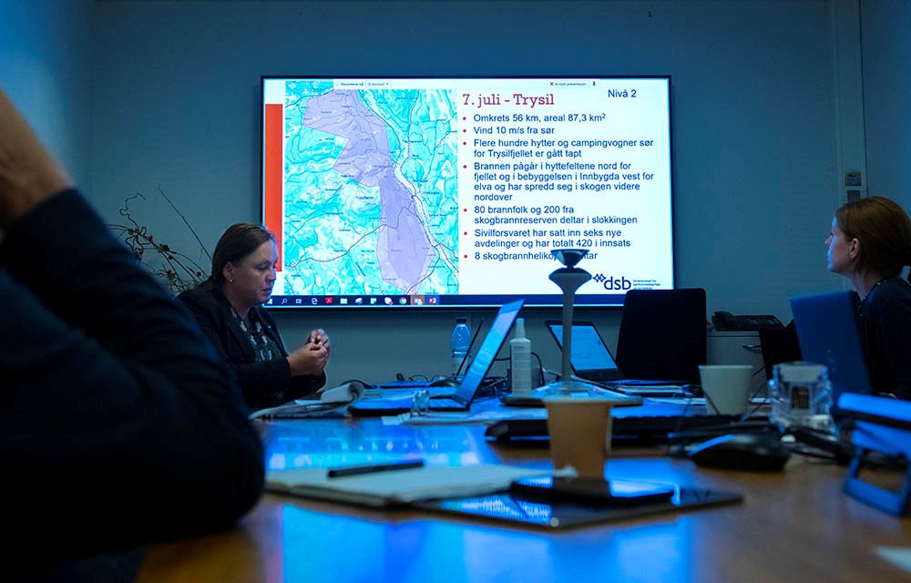 Personer i møterom foran presentasjon med kart