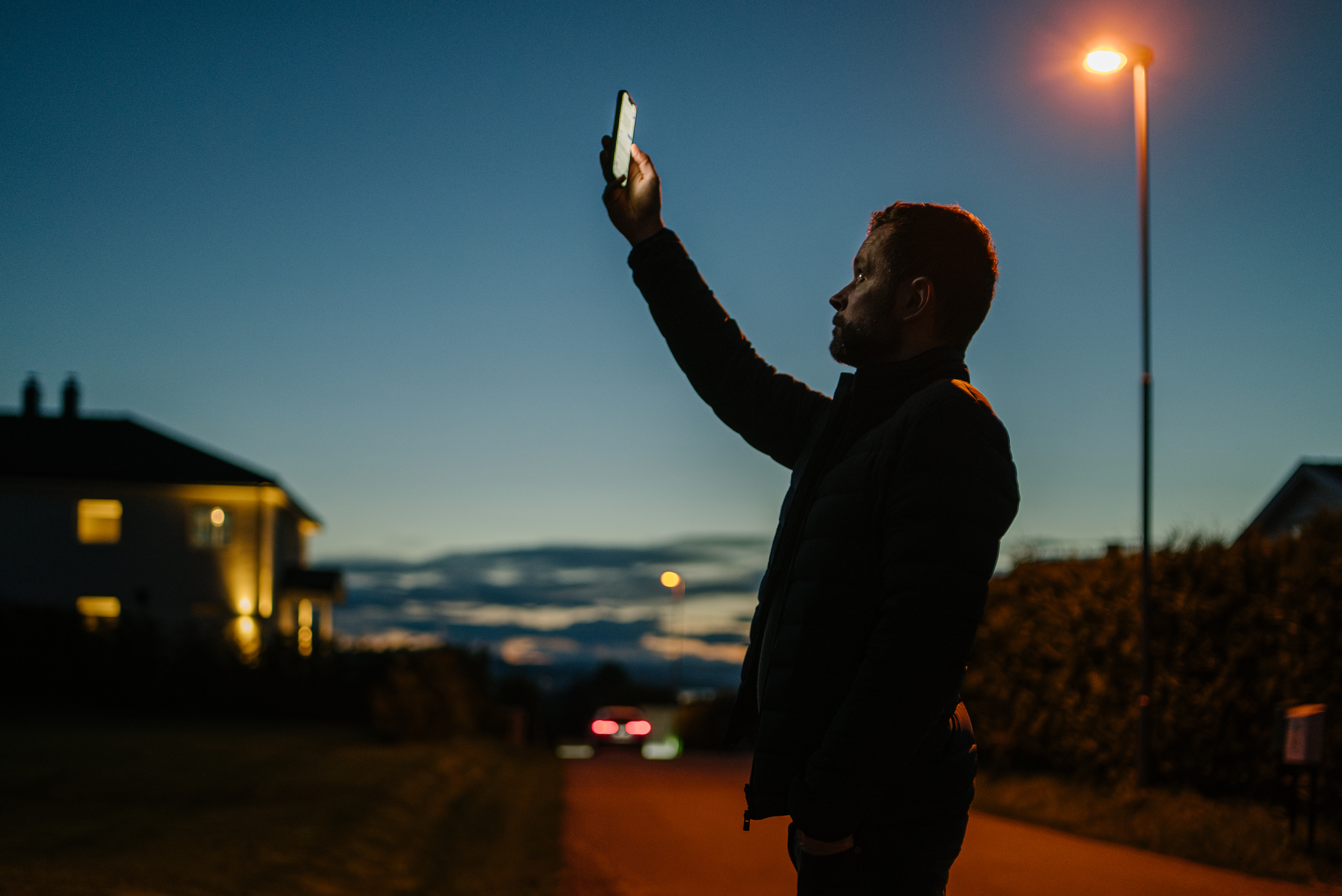 A person holds a mobile phone up in the air, in an attempt to get mobile coverage.