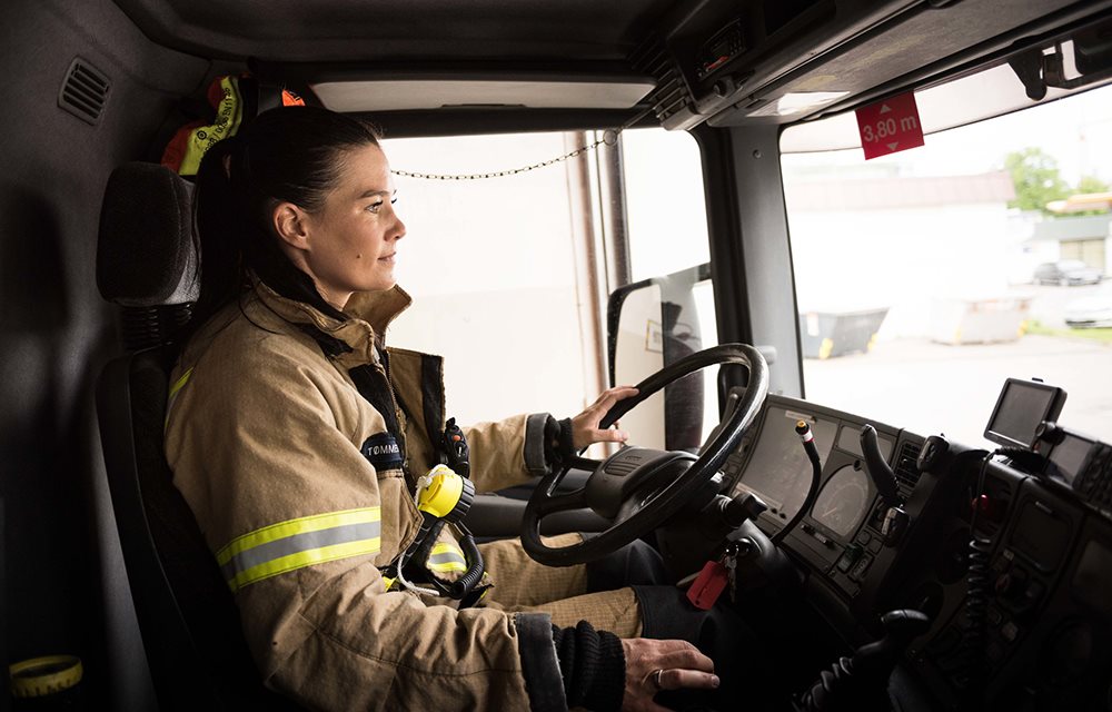 Kvinnelig brannkonstabel som kjører brannbil