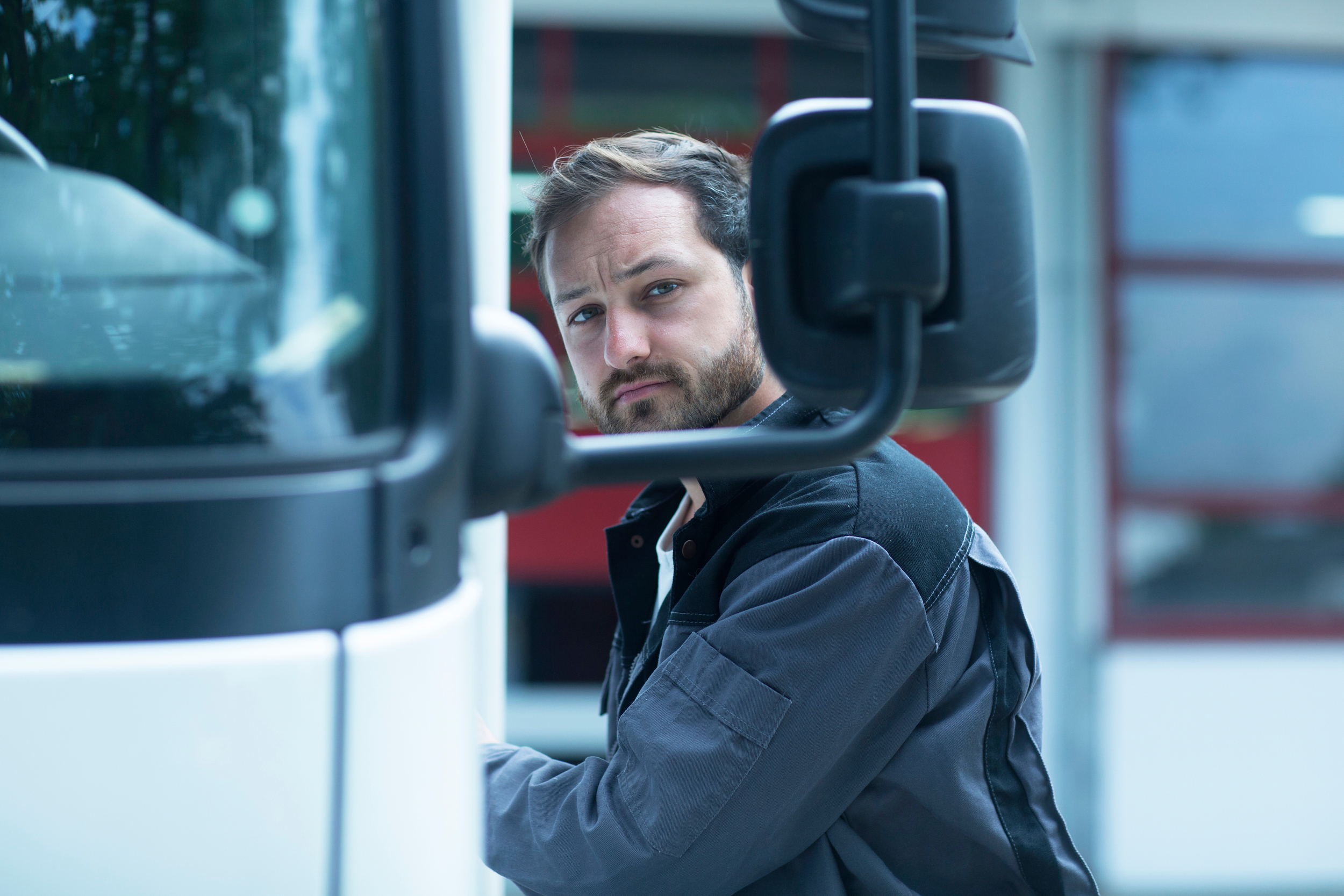 Mannlig lastebilsjafør som står ved siden av bilen