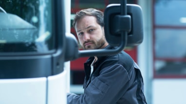 Mannlig lastebilsjafør som står ved siden av bilen