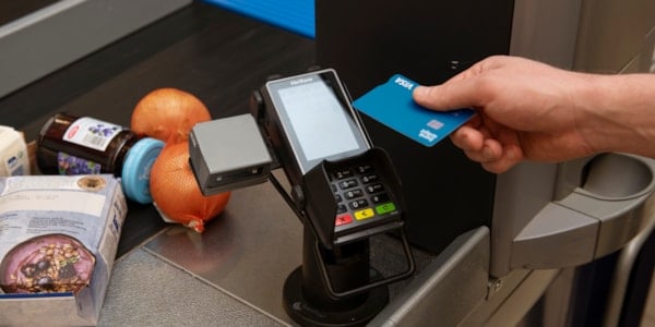 Ei hand som held eit betalingskort mot ein betalingsteminal.