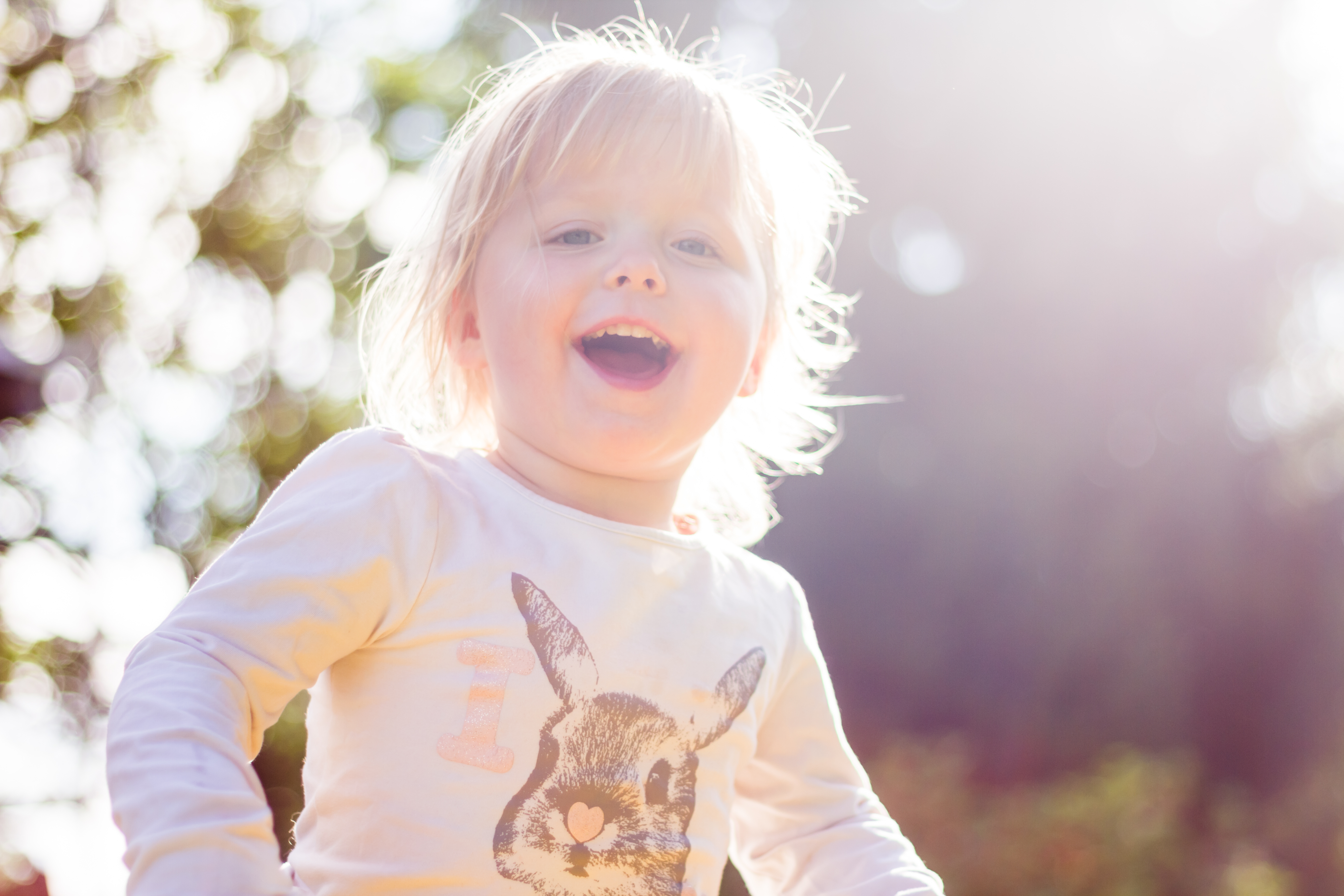 Liten jente som smiler i solskinn