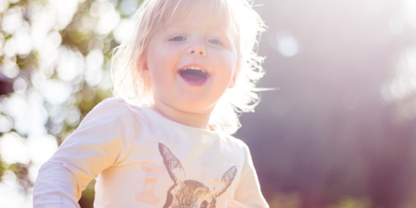 Liten jente som smiler i solskinn