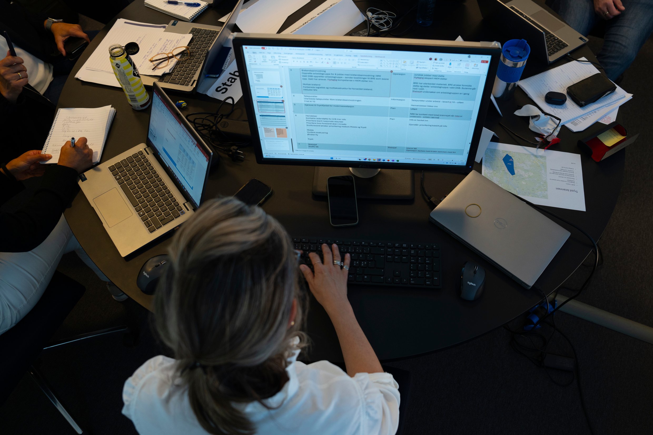 Kvinne foran tastatur og pc-skjerm sett ovenfra