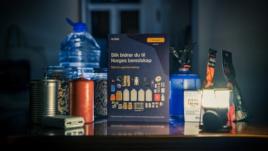 Vanndunk, tørrmat og egenberedskapsbrosjyre oppstilt på et bord med mørk bakgrunn