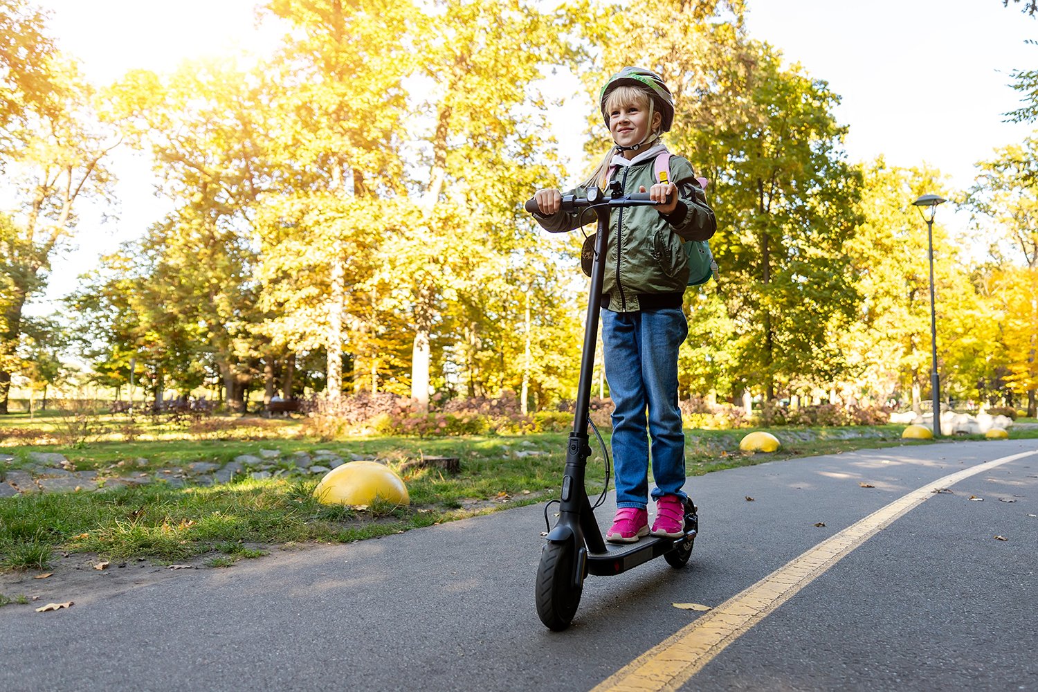 Smiling girl with helmet riding electric scooter.