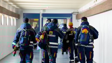 Sivilforsvarsmannskaper sett bakfra gående i en gang