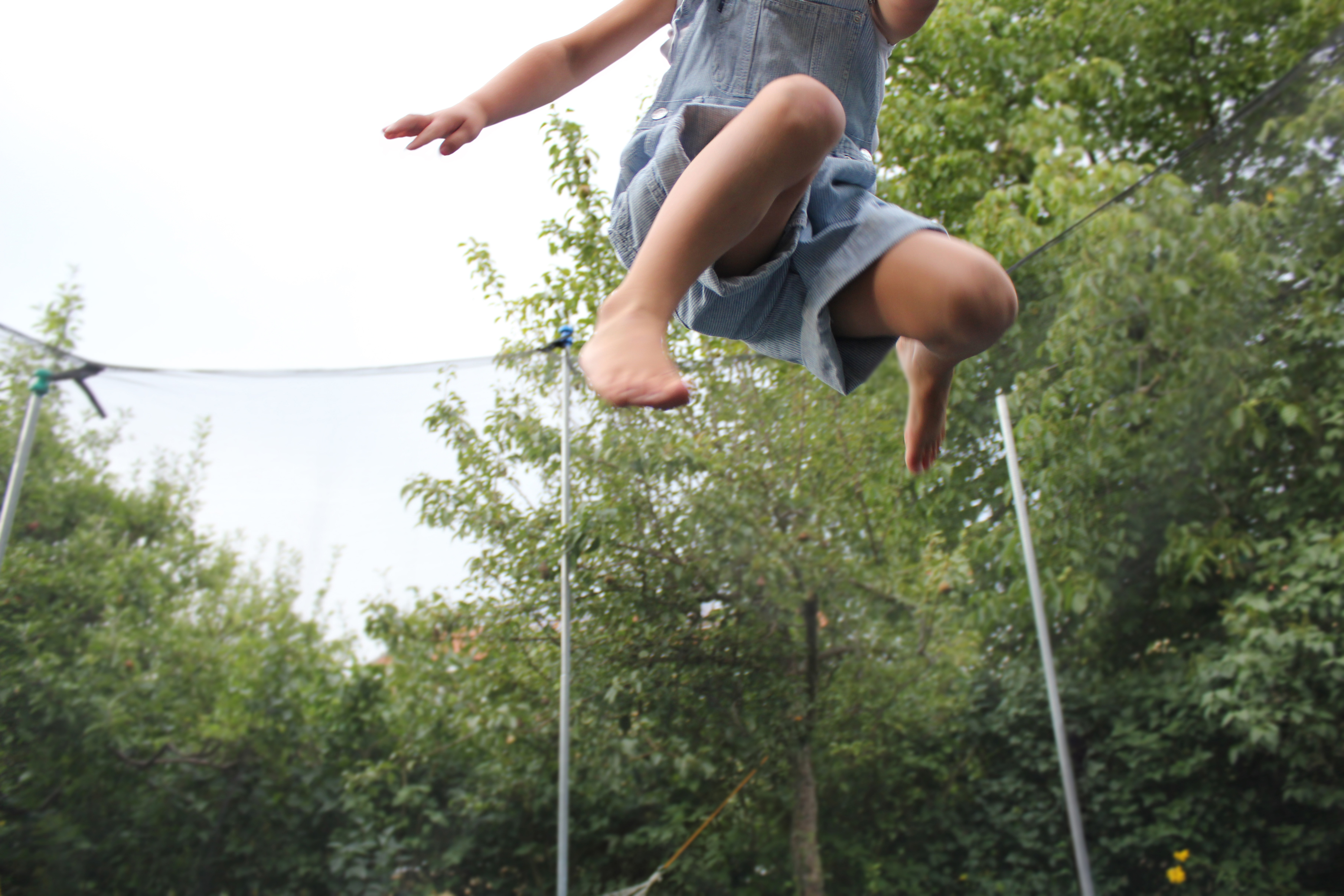 The lower body of a child who is in the air above a trampoline