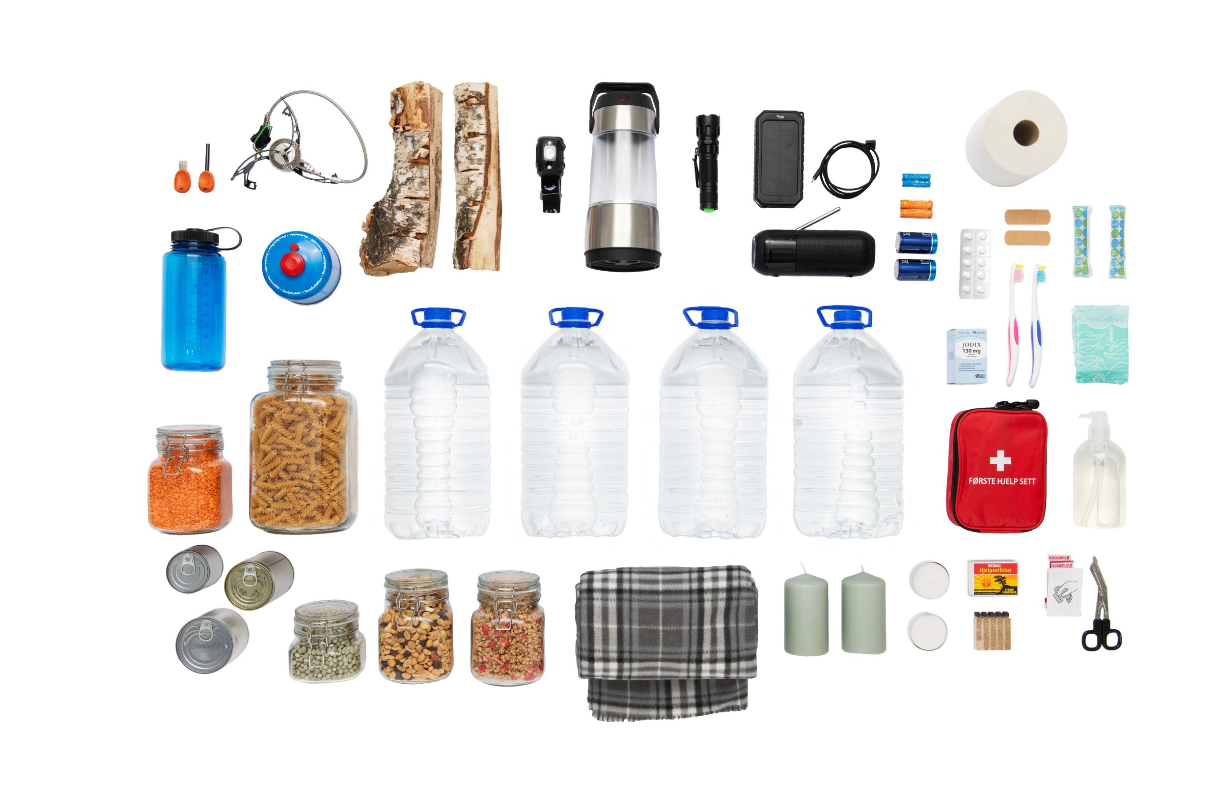Nødutstyr for beredskap, inkludert vannflasker, matvarer i bokser og glass, lommelykt, fyrstikker, teppe, førstehjelpssett, hygieneartikler, vedkubber og campingutstyr, arrangert på hvit bakgrunn.
