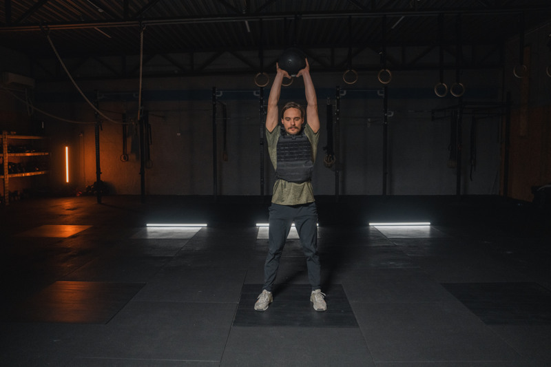 Mann som løfter en medisinball over hodet i et treningsstudio