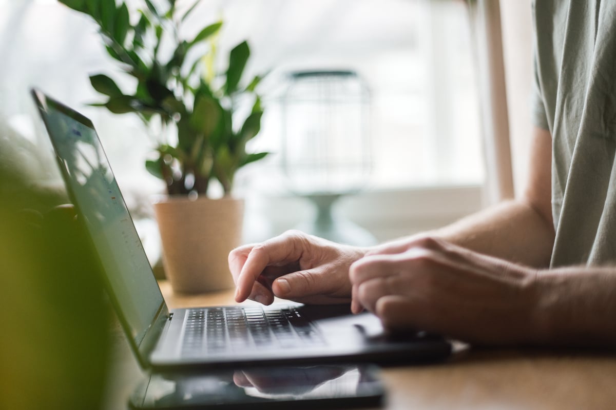 To hender som skriver på et tastatur på en laptop