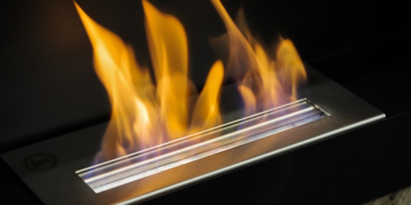 Bioetanolpeis som brenner med oransje flammer. Bakgrunnen er sort.