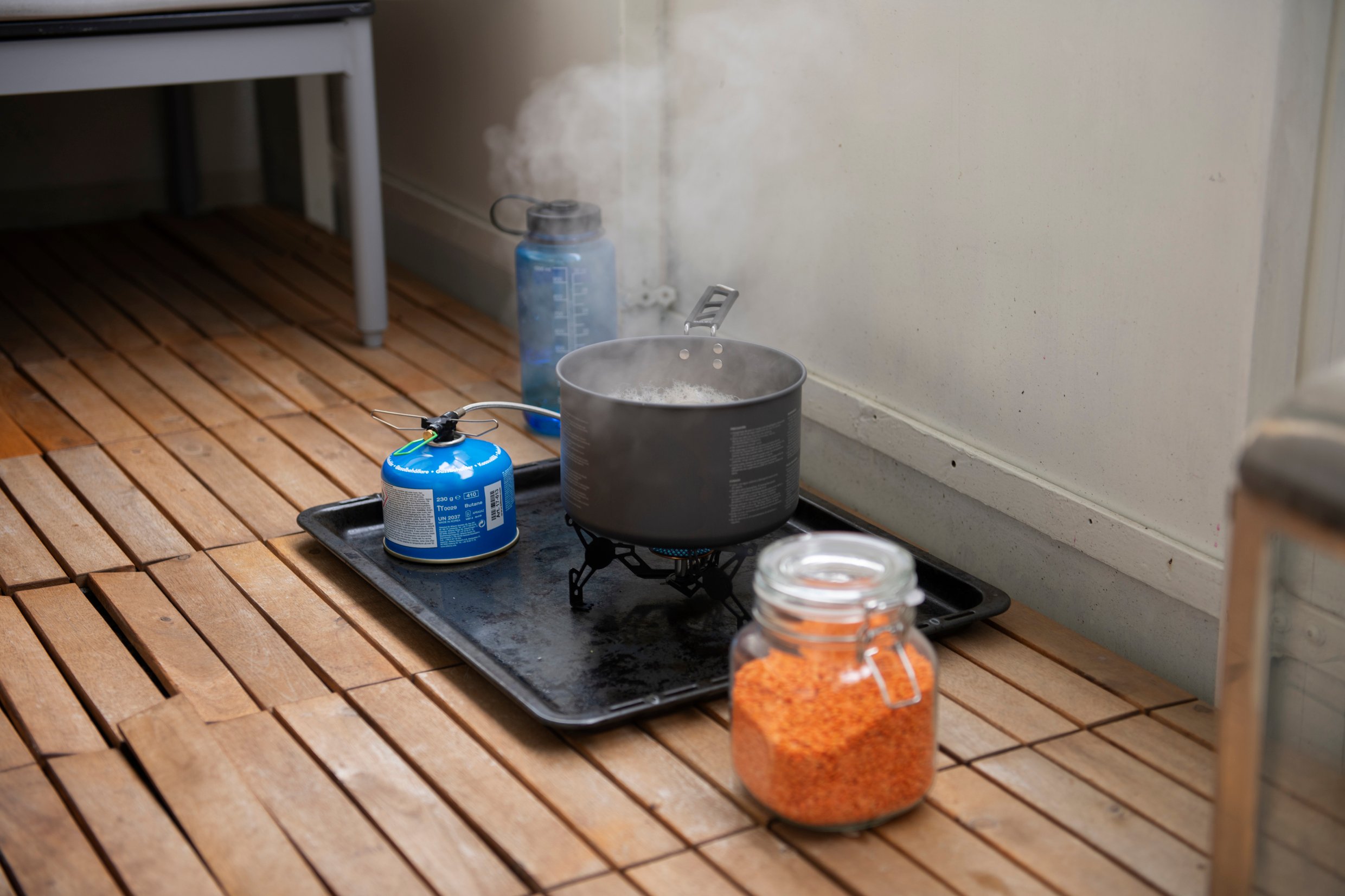 Food is prepared on hiking equipment outside on a balcony.