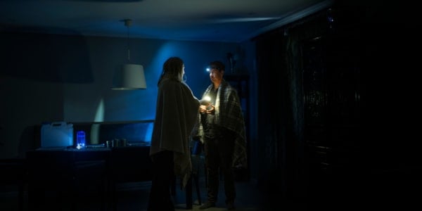 En mann og en kvinne med ulltepper over skuldrene i et mørkt rom.