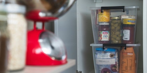 Mann som holder en liten jente på armen mens han skyver en handlevogn full med varer foran seg. På siden går det to unge gutter som bærer en vannkanne og en lykt.