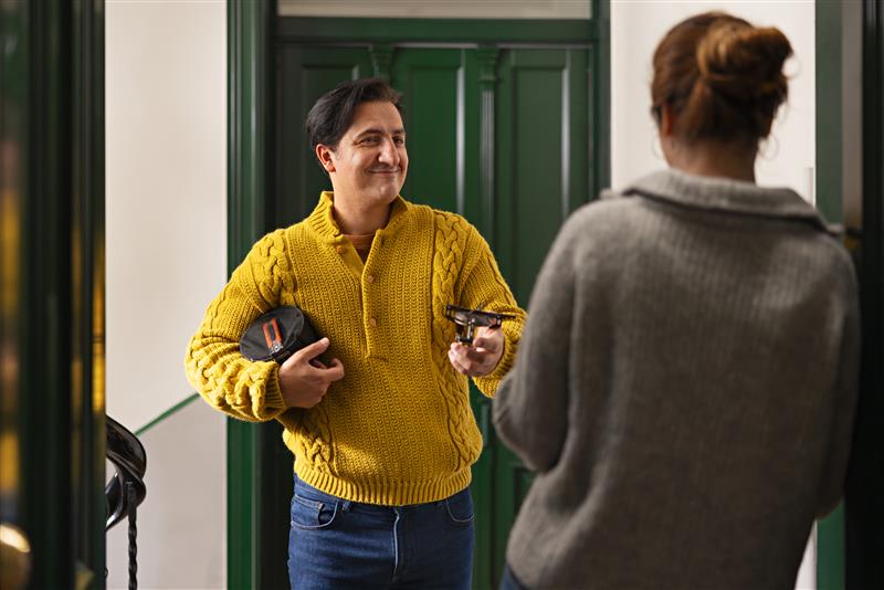 Mann med gul genser i trappeoppgang som står utenfor hos en nabo