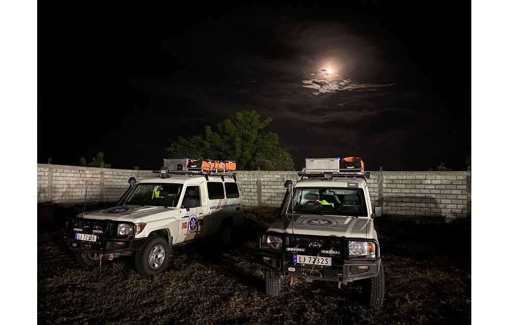 Ambulanser foran mur under mørk himmel