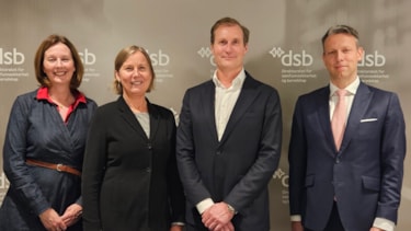 Smilende representanter fra DSB og Motorola oppstilt på rekke foran en bakvegg med DSB-logo