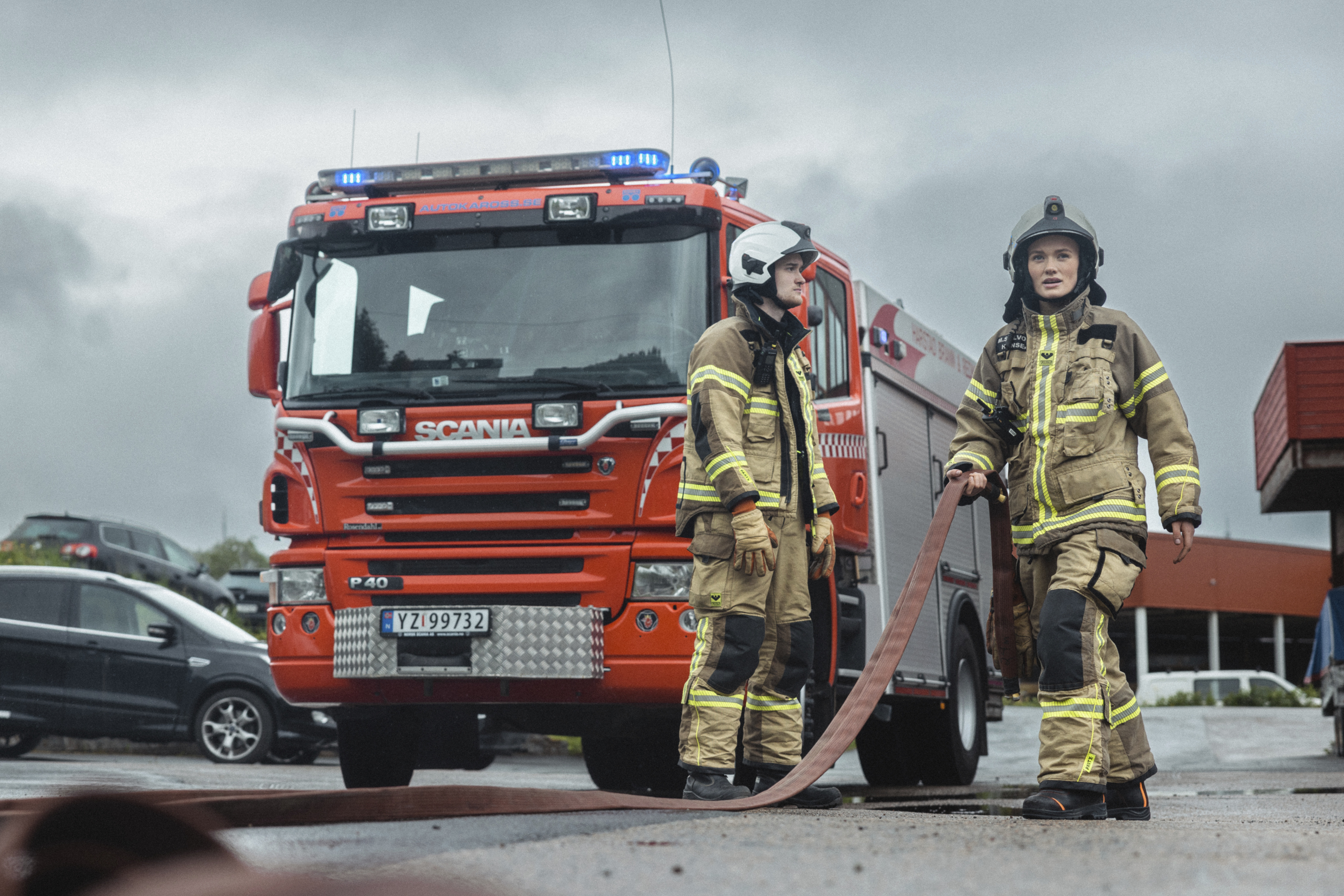 Brann- og redningsmannskaper ruller ut slange foran brannbil