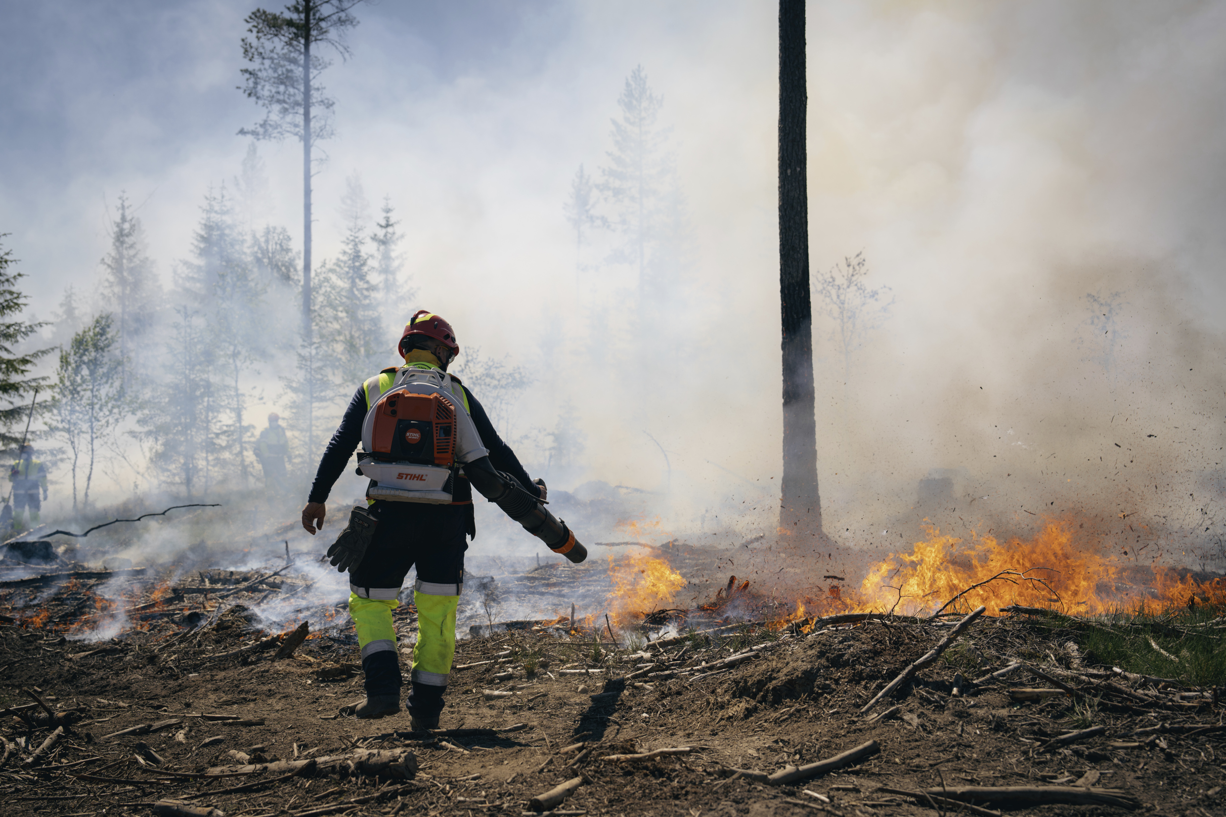 Brannmann som slokker åpne flammer i skogsterreng