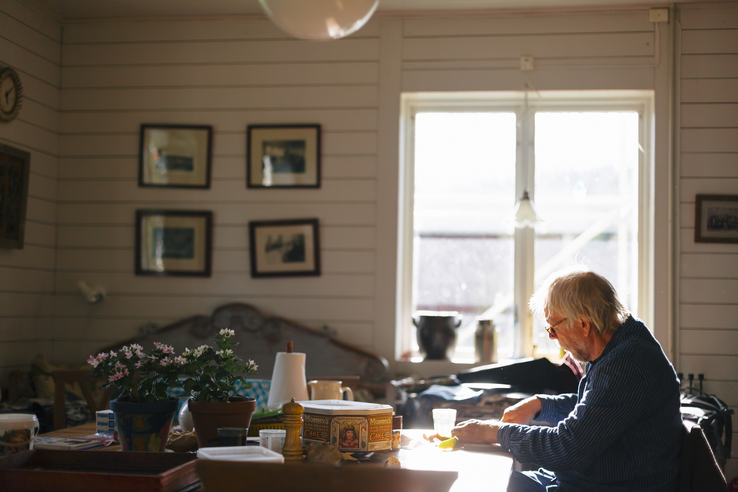 Eldre mann som spiser alene i et rotete kjøkken