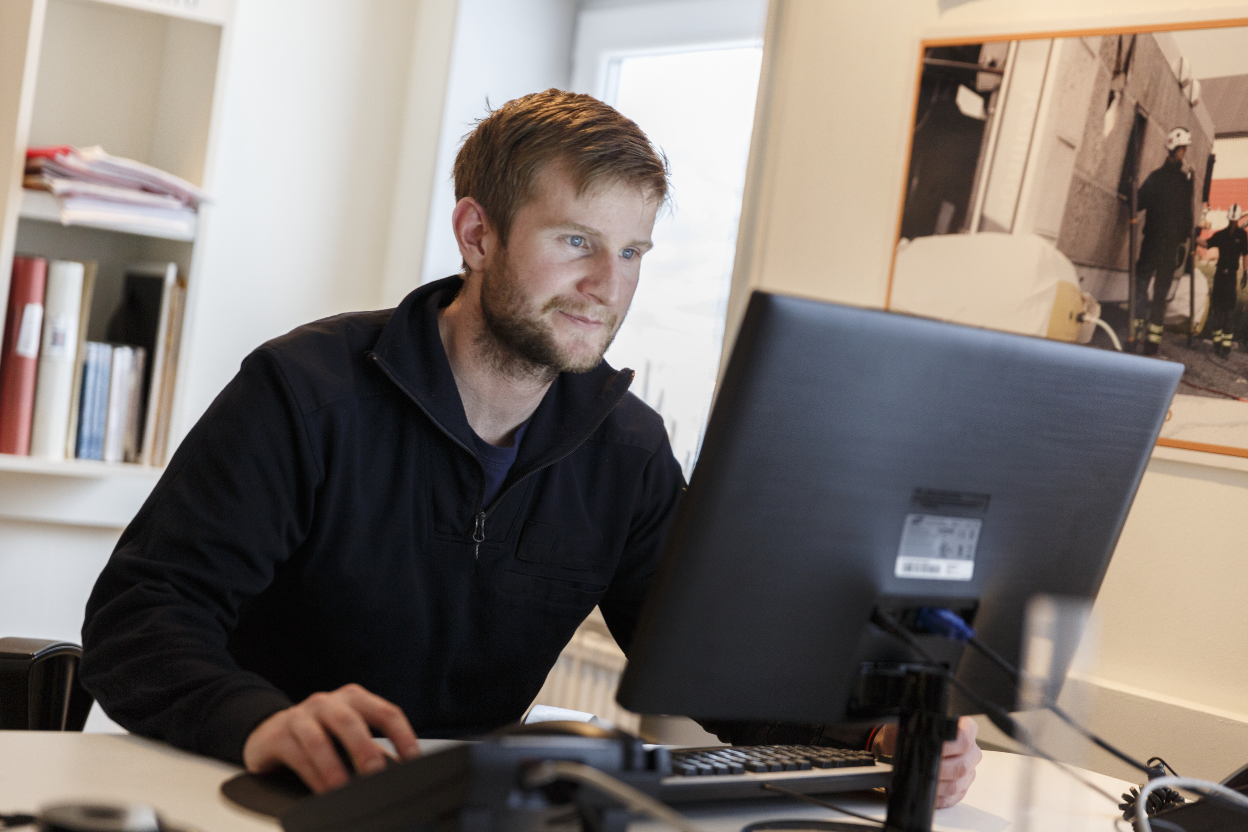 Mann som sitter på kontor og ser på en dataskjerm