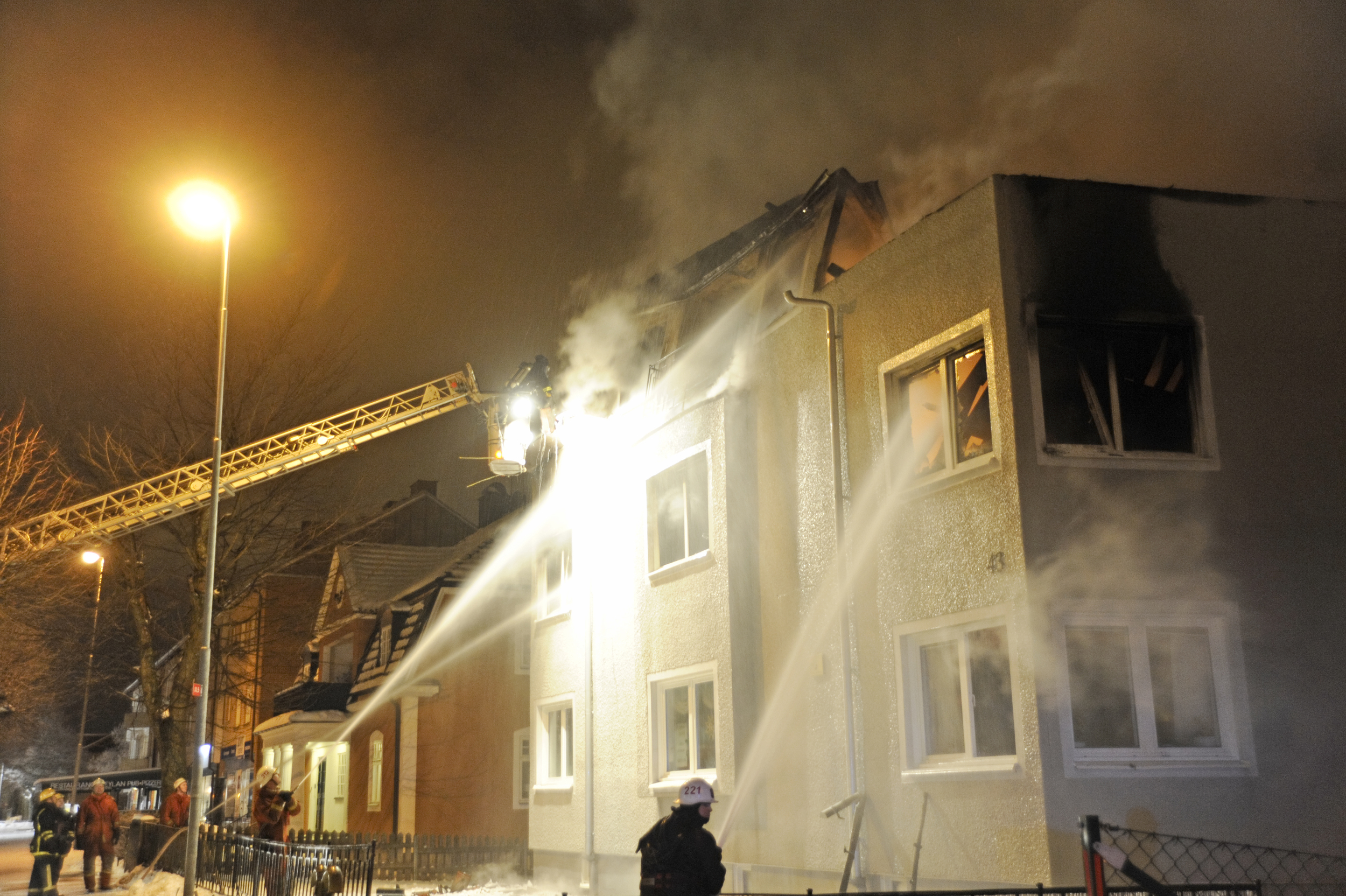 Brannmannskaper som spyler vann på en brennende leilighetsbygning