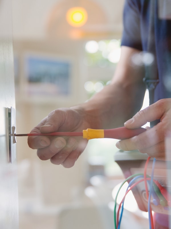 Elektriker som arbeider med skrutrekker i en lys vippe i moderne rom