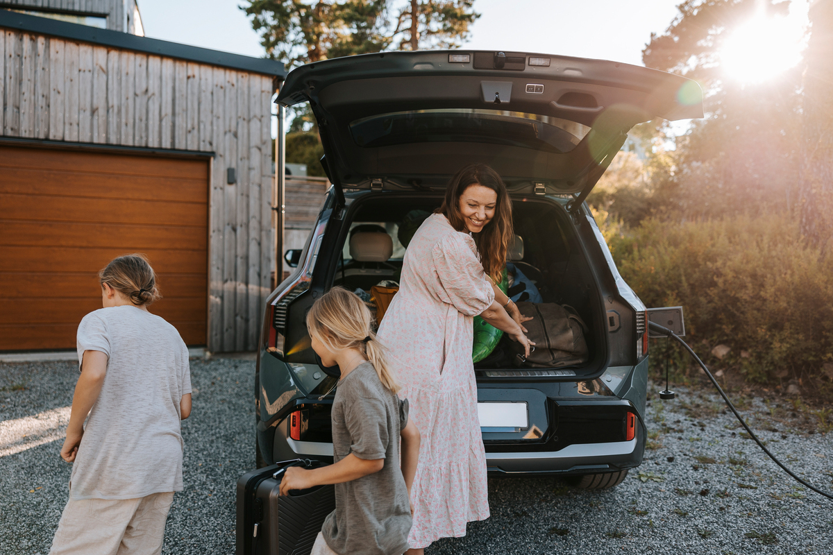 Kvinne og barn  som pakker bilen mens den står til lading