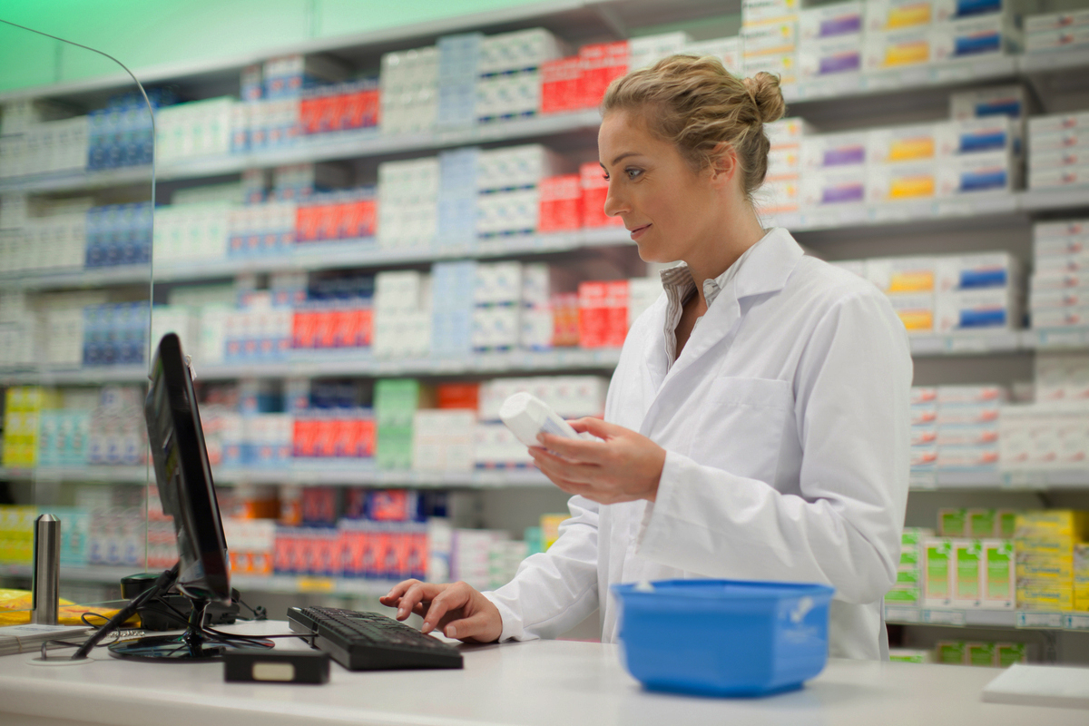 Apotekansatt som gjør undersøkelser av en vare på pc'en
