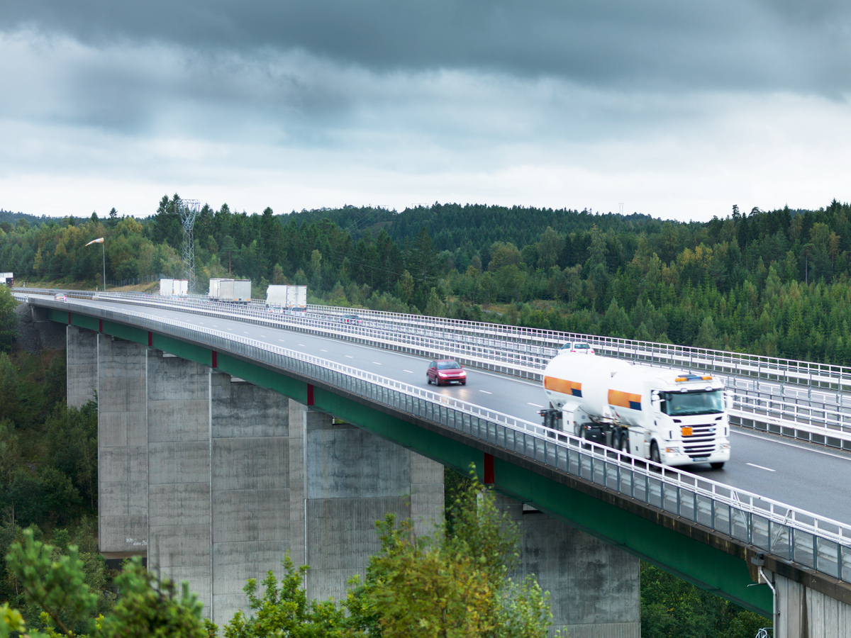 Tankbil og personbiler som kjører over en stor bro