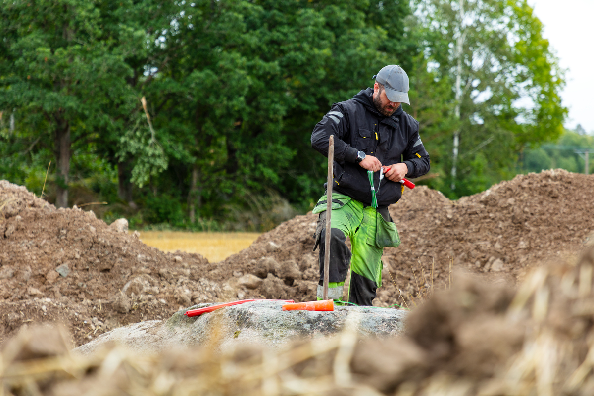 Kvinne med arbeidsklær og hjelp som peker på en byggeplass