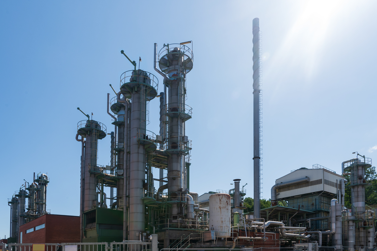 Industribygg med pipe som ryker mot blå himmel