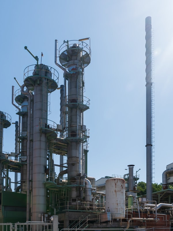 Industribygg med pipe som ryker mot blå himmel