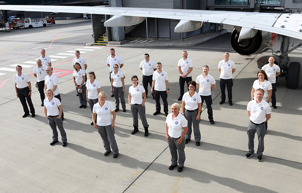 Team av NOR EMT-medlemmer oppstilt på flyplass foran fly