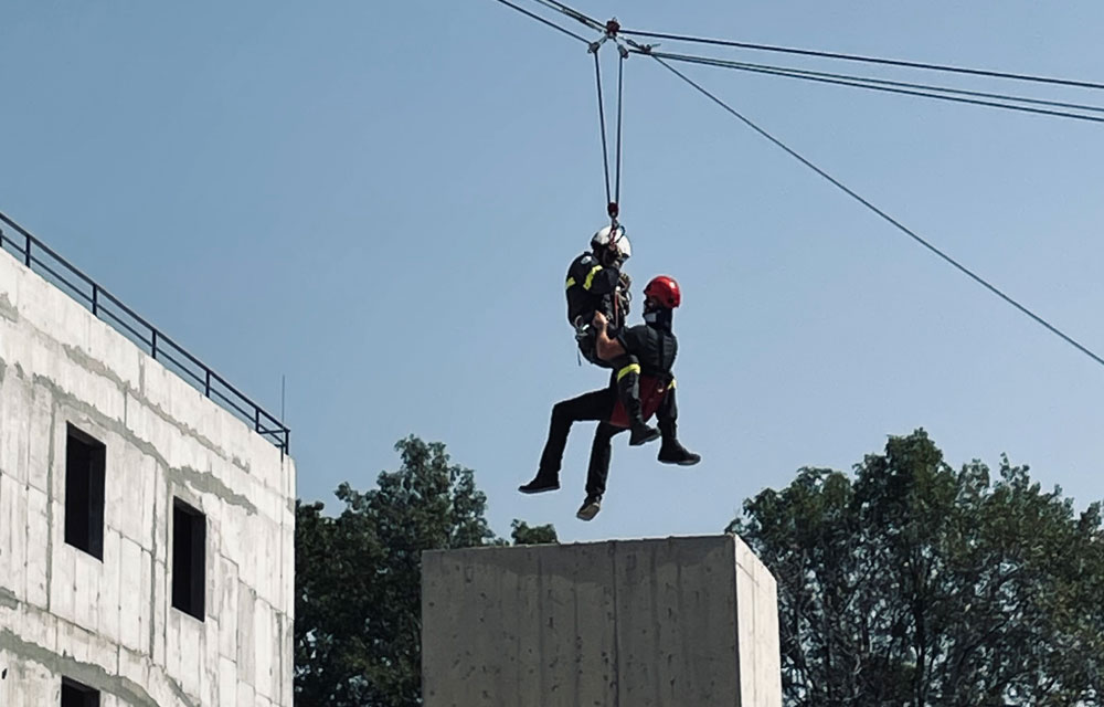 To personer som henger i klatresele fra en wire mellom bygninger