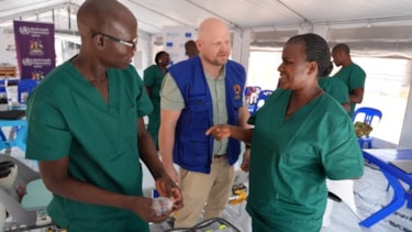 Norsk ekspert side om side med lokalt helsepersonell kjedd i grønt