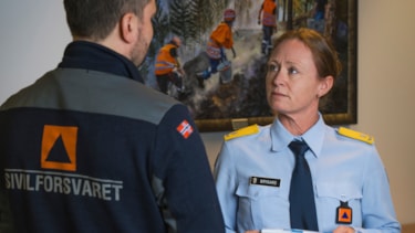 Mona Brygard i sivilforsvarsuniform snakker med kollega