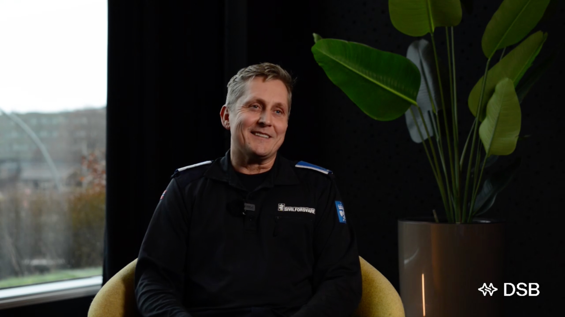 Frode Schumaker i sivilforsvarsuniform foran mørk bakvegg