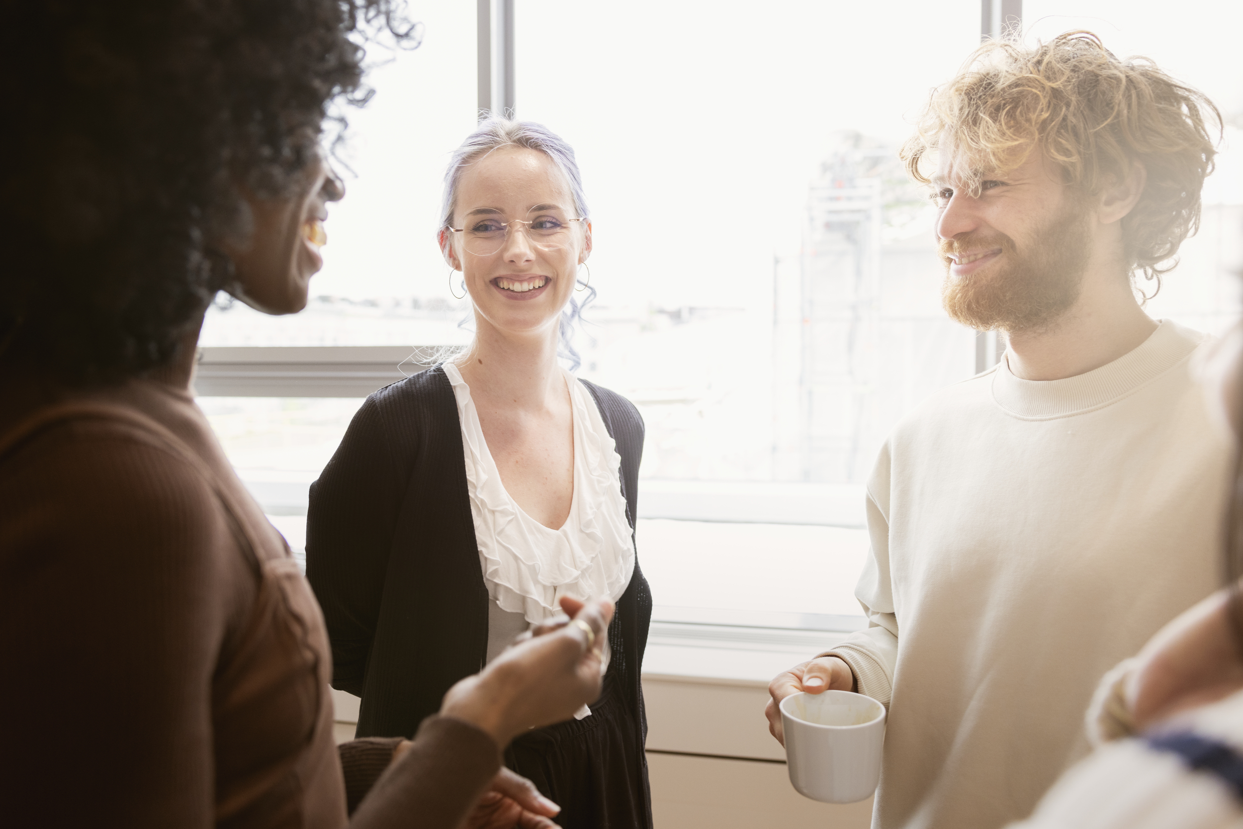 Gruppe mennesker som står og snakker sammen i et kontorlokale