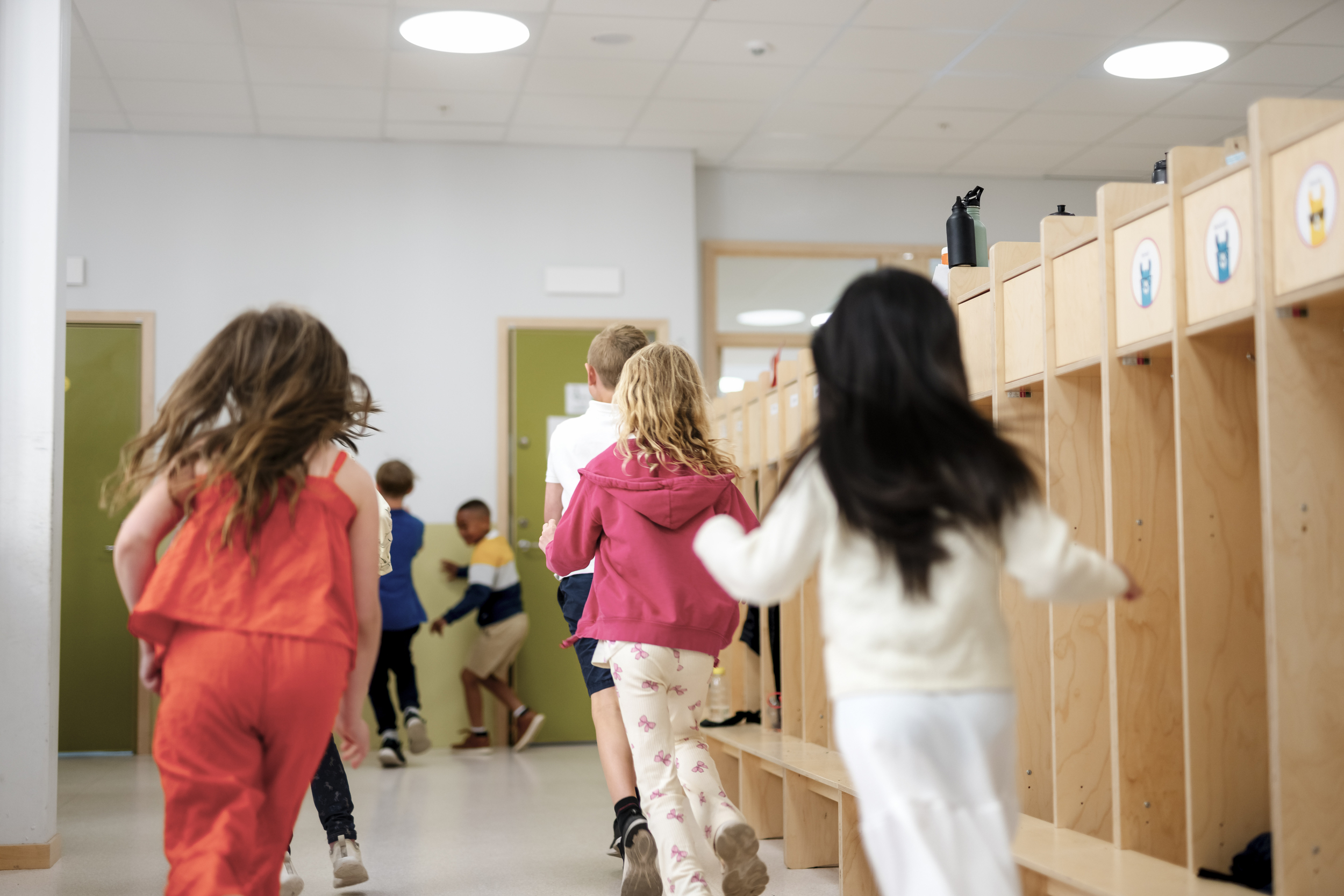 Barn som løper i en garderobe på en skole eller barnehage