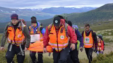 Gruppe med redningsarbeidere som går i fjellet