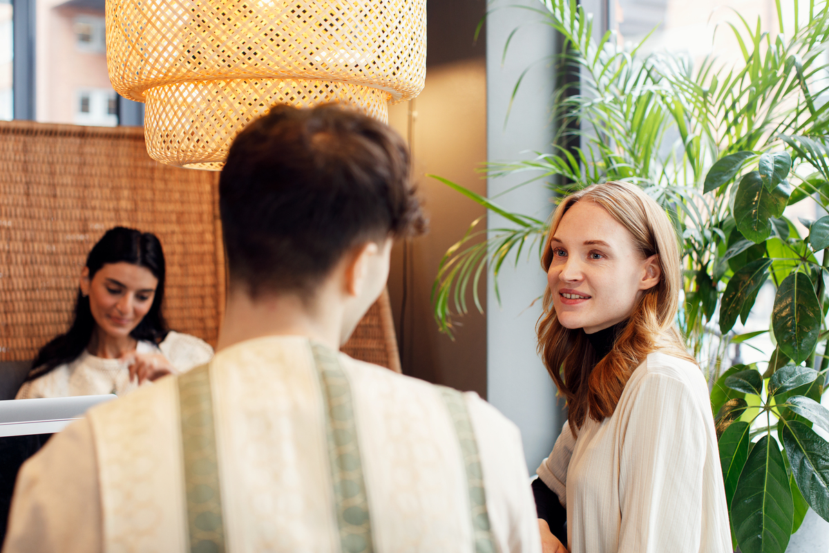 Kollegaer som har møte på en cafe. I bakgrunnen står en grønn plante.