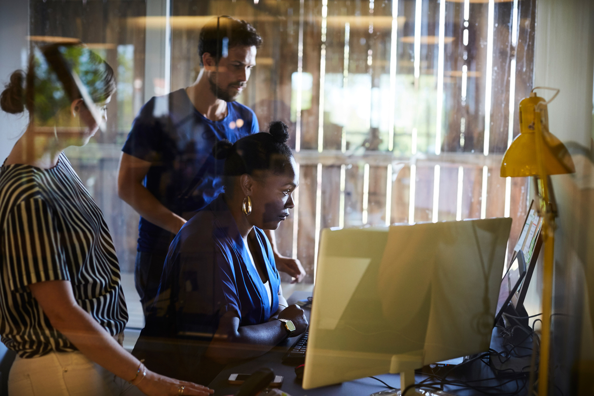 Gruppe mennesker som står rundt og ser på samme pc-skjerm