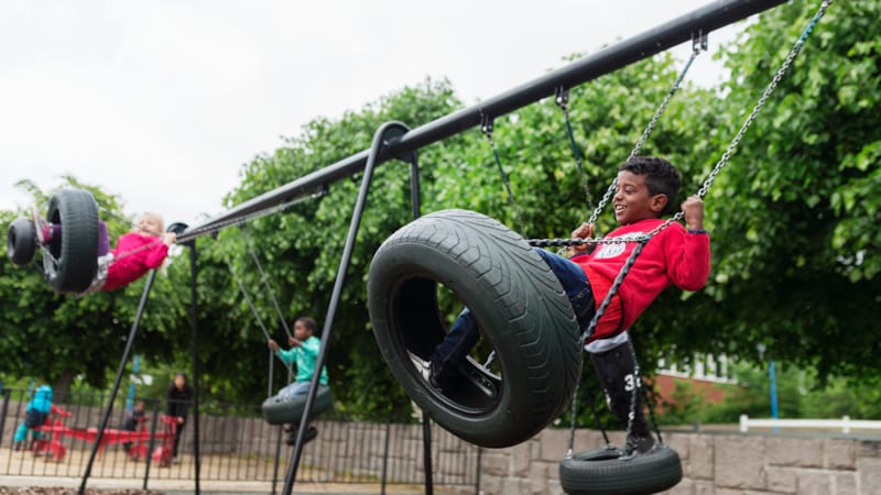 Små barn som sitter på huske på en lekeplass