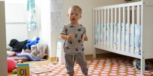 Liten gutt står i et barnerom og holder to puslebrikker