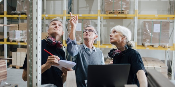 Kvinne og to menn som inspiserer et lager