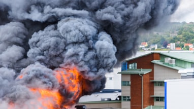 Sort røyk og flammer som stiger opp fra en bygning